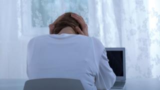 mujer de espaldas frente a computadora.