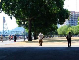 Homeless people walk by the water's edge in Portland