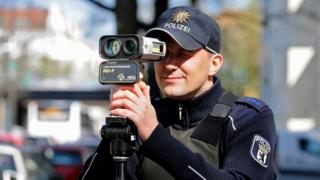 A German police officer holds a portable laser speed trap to his eye in this 2016 file photo