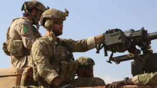 Armed men in uniform identified by Syrian Democratic forces as US special operations ride in the back of a pickup truck in the northern Syrian province of Raqqa on May 25, 2016.