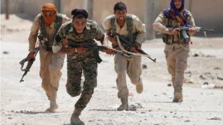 Kurdish fighters run across a street in Raqqa (03/07/17)