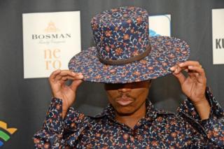 A man tips his printed hat, which matches the print on his shirt, on the red carpet at the South African Film and Television Awards (SAFTAs) at the Sun City Superbowl on 2 March 2019, in Rustenburg.