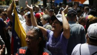 Manifestantes batem palmas e levantam bandeira do país em Caracas