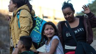 A group of Central American migrants surrender to US Border Patrol agents after jumping over the metal barrier separating Playas de Tijuana in Mexico from the US, 2 December 2018