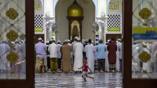 Thai men attend the evening prayer as a boy runs through the central Pattani Mosque in Pattani, Thailand.