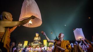 Buddhist monk setting a lamp go.