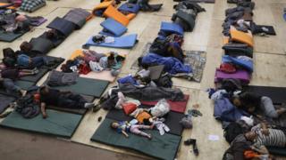 Migrantes deitados em colchonetes