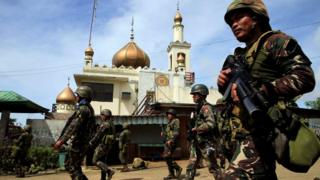 Перед нападением правительственные войска проходят мимо мечети с повстанцами из так называемой группы Мауте, которые захватили большую часть города Марави на юге Филиппин 25 мая 2017 г.