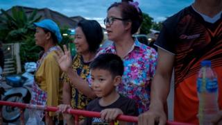 Onlookers watch and cheer as ambulances transport the 10th rescued schoolboy from a helipad nearby to Chiangrai Prachanukroh Hospital on July 10, 2018 in Chiang Rai, Thailand