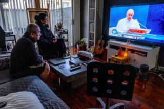 Miguels Familie sieht zu, wie der Papst im Fernsehen einen Segen gibt