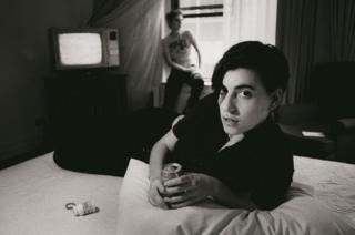 positive news Elastica's Justine Frischmann on a hotel bed drinking a can of lager