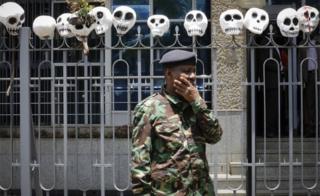 A police officer looks on in front of the mock skulls put on top of a fence guarding the Central Bank of Kenya during a protest against the politicians and leaders of war-torn South Sudan, in Nairobi, Kenya, 11 October 2018.