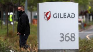 Man near a sign in front of the Gilead Sciences headquarters