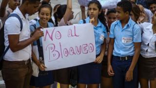 Estudiantes en La Habana sostienen un cartel con la leyenda "No al bloqueo".