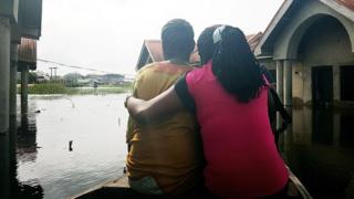 LAGOS, NIGERIA - OCTOBER 7: A couple is seen on a boat after the Ogun region flooded following a day long torrential rain caused Ogun river to overflow in Lagos, Nigeria on October 7, 2016.