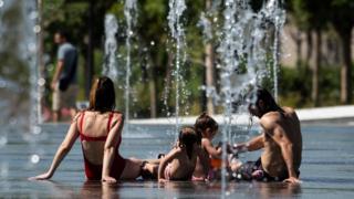 People cool off in water fountains at Parc Central amid a heatwave in Valencia