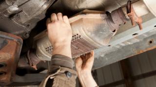 A catalytic converter being removed from an SUV car