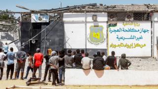በሊቢያ፣ ትሪፖሊ የሊቢያ መንግሥት ስደተኞችን በሚያቆይበት ጣቢያ ደጃፍ ቆመው