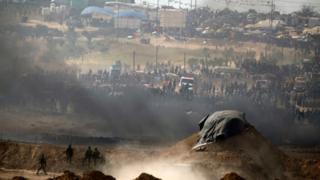 Israeli soldiers take positions on the other side of the border fence from Palestinians