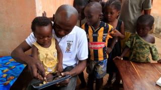 Un père montre à son bébé comment utiliser une tablette