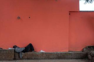A homeless man lies asleep in the middle of the day on an empty street in Westlands, Nairobi.