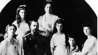 Tsar Nicholas II sits with his family - his wife, Tsarina Alexander, leans on the back of her chair and his children sit around him