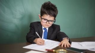 A small boy - pretending to be a grown-up - working hard at a desk