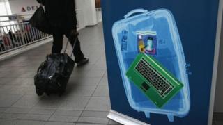L'affiche d'un ordinateur portable dans le hall d'un aéroport, avec un voyageur au second plan