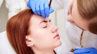 Beautician working on a woman's eyebrows