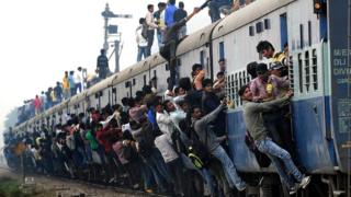 Люди висят на внешней стороне поезда в Индии