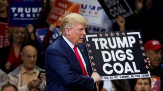 Дональд Трамп держит знак поддержки угля во время ралли