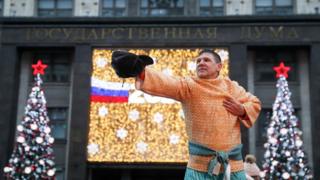 Артист в национальном костюме на фоне Госдумы и елок