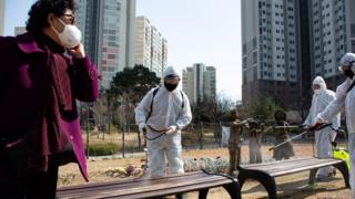 Местные жители распыляют дезинфицирующее средство в своем районе в качестве меры предосторожности против вспышки коронавируса в Сеуле, Южная Корея, 23 марта 2020 г.