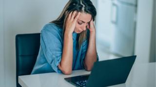 woman at computer with head in hands