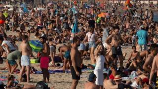Beachgoers bask in the sun as they enjoy a warm afternoon in Barcelona on 17 July