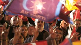 Supporters wave flags and banners as Turkish President and presidential candidate Recep Tayyip Erdogan makes an address