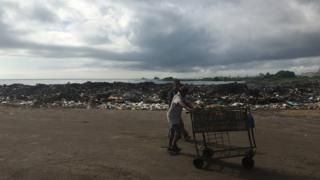 Pessoas caminham ao lado de lixão em Maracaibo, na Venezuela