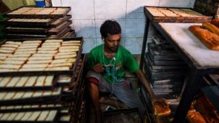 An Indian man listens to music on earphones as he works at a local bakery in the old quarters of New Delhi on July 20, 2016.