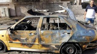 A destroyed vehicle is seen at the site of car bomb attack in Baghdad (13 July 2015)