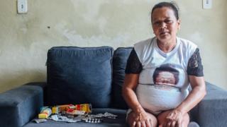 Josilene Batista sentada no sofá da casa do filho