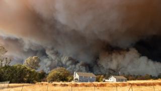 A home is overshadowed by towering smoke plumes as the Camp fire races through California on November 8 2018