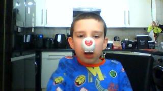 A young boy wearing a red nose.