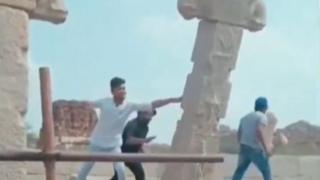 Screengrab from a viral video showing three men shoving a pillar in Hampi