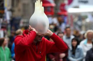 Street performer puts rubber glove over his head