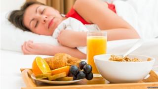 Mujer durmiendo frente a una bandeja de desayuno