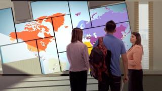 Una trabajadora de Laureate le muestra un mapa mundi a unos alumnos