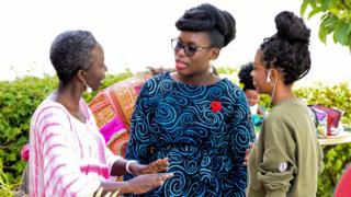 Liliane Coulibaly, propriétaire d'un salon de coiffure pour cheveux naturels (au centre) discutant avec une femme et une jeune fille lors du Dakar Hair Day.