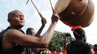 Мужчина играет на барабане, собираясь с другими ганскими скорбящими, чтобы посмотреть на гроб с останками покойного президента Ганы Джона Атта Миллса, проезжающий по улицам Аккры, из парламентского комплекса Государственного дома, где он пролежал в штате с 8 августа , 2012, на Майдан Независимости, для панихиды