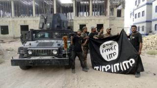 Iraqi security forces hold an Islamist State flag which they pulled down at the University of Anbar, in Anbar province on 26 July 2015
