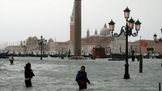 People walk on the flooded St. Mark's Square in Venice on October 29, 2018